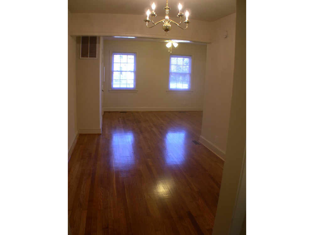 an empty living room with wood floors and a chandelier